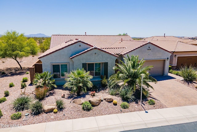 mediterranean / spanish-style home with a garage, a tile roof, decorative driveway, a mountain view, and stucco siding