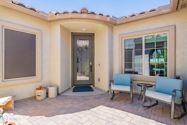 property entrance featuring a patio, a tiled roof, and stucco siding