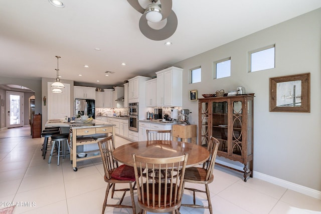 dining room featuring arched walkways, light tile patterned flooring, baseboards, and recessed lighting