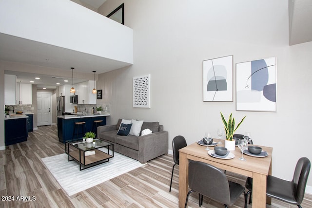 living room featuring sink, a towering ceiling, and light hardwood / wood-style flooring