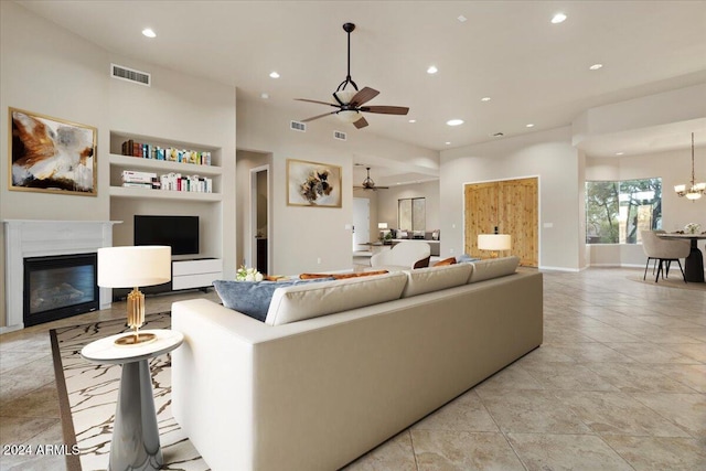 living room with built in shelves and ceiling fan with notable chandelier