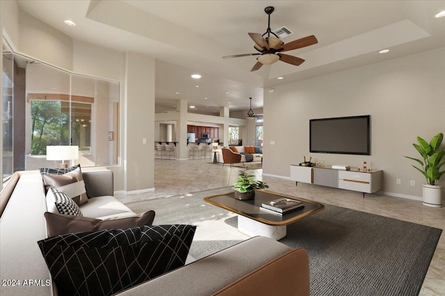 living room with ceiling fan and a tray ceiling