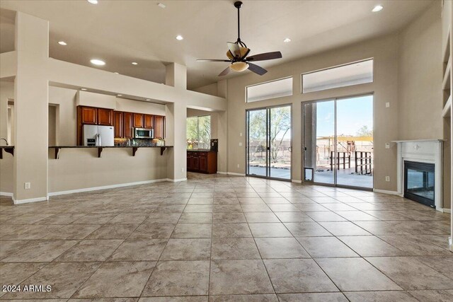 36908 N 19th St, Phoenix, AZ 85086 - unfurnished living room featuring ceiling fan, recessed lighting, baseboards, a glass covered fireplace, and a towering ceiling