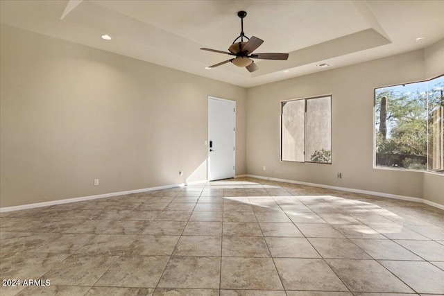 empty room featuring a raised ceiling and ceiling fan