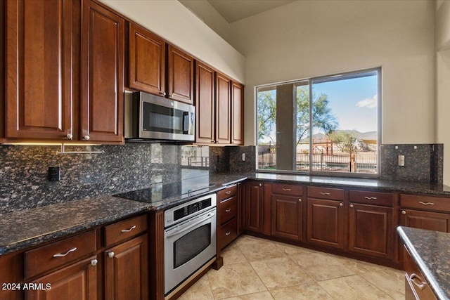 kitchen featuring dark stone countertops, decorative backsplash, light tile patterned floors, and stainless steel appliances