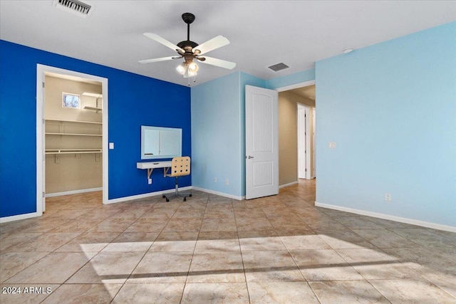 unfurnished bedroom with a spacious closet, a closet, and ceiling fan