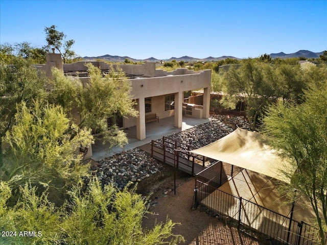 back of property with a mountain view and a patio