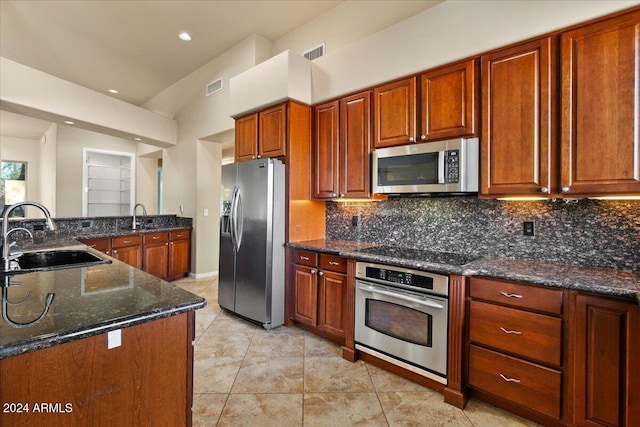 kitchen with decorative backsplash, dark stone countertops, sink, and stainless steel appliances