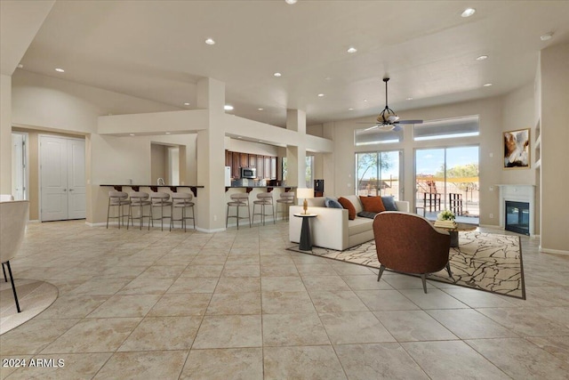 tiled living room featuring ceiling fan and a towering ceiling