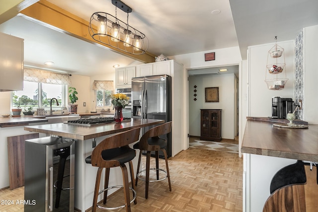 kitchen with stainless steel appliances, beverage cooler, light parquet flooring, white cabinets, and sink