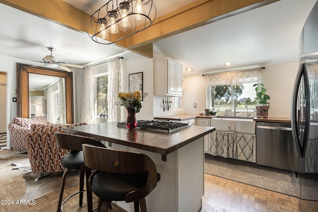 kitchen featuring light parquet flooring, white cabinets, ceiling fan, and stainless steel appliances