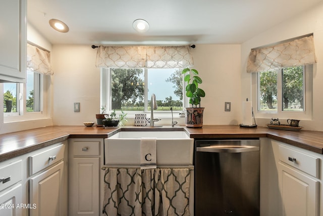 kitchen with white cabinets, butcher block countertops, dishwasher, and sink