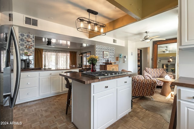 kitchen with a kitchen bar, white cabinets, black fridge, and wooden counters