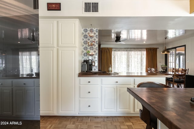 kitchen with ceiling fan, light parquet floors, butcher block countertops, and white cabinets