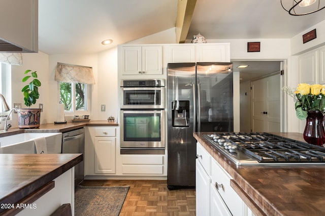 kitchen with butcher block countertops, beamed ceiling, stainless steel appliances, and dark parquet floors