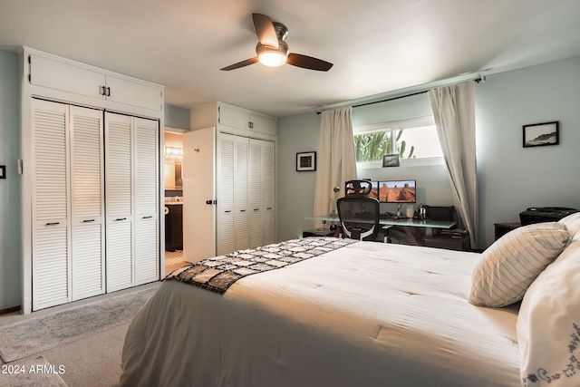 bedroom featuring ceiling fan, light colored carpet, and multiple closets