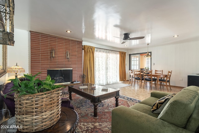 living room featuring ceiling fan, parquet flooring, and a fireplace