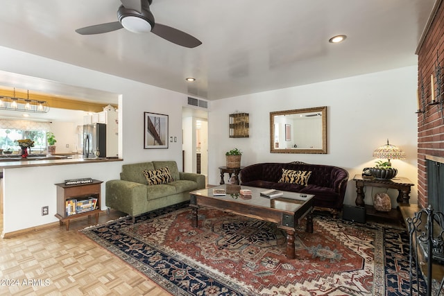 living room featuring a brick fireplace, light parquet flooring, and ceiling fan