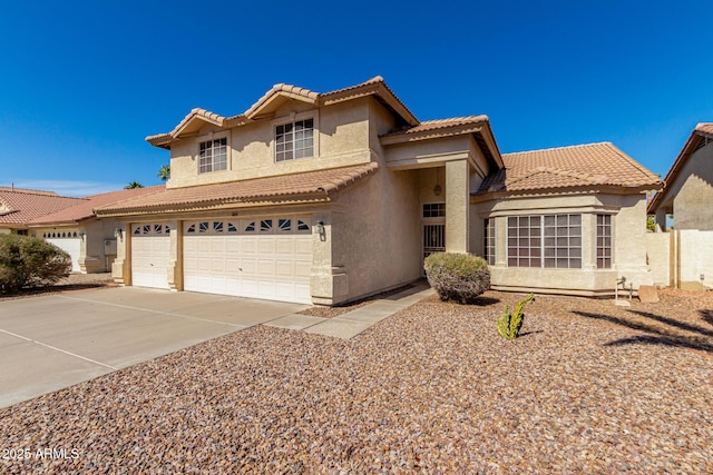 view of front of house with driveway, a tiled roof, a garage, and stucco siding