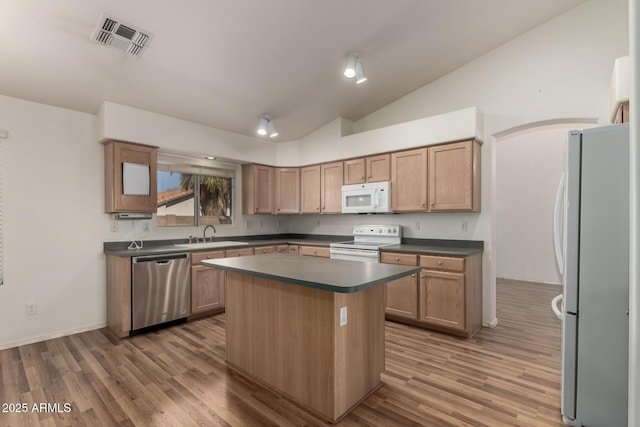 kitchen with white appliances, visible vents, dark countertops, a center island, and vaulted ceiling