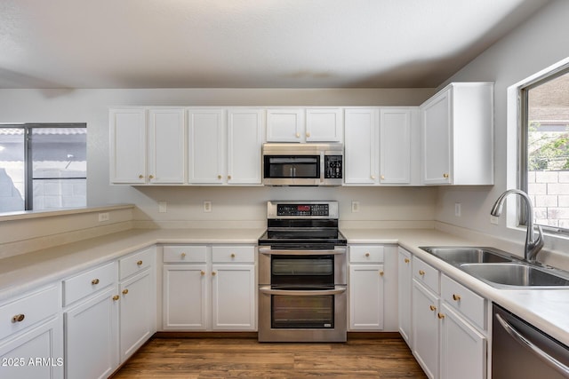 kitchen featuring a sink, dark wood finished floors, stainless steel appliances, white cabinets, and light countertops