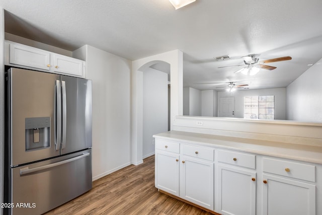 kitchen with visible vents, stainless steel fridge, light countertops, and white cabinetry