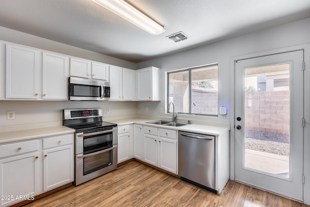 kitchen with visible vents, a sink, white cabinetry, appliances with stainless steel finishes, and light wood finished floors