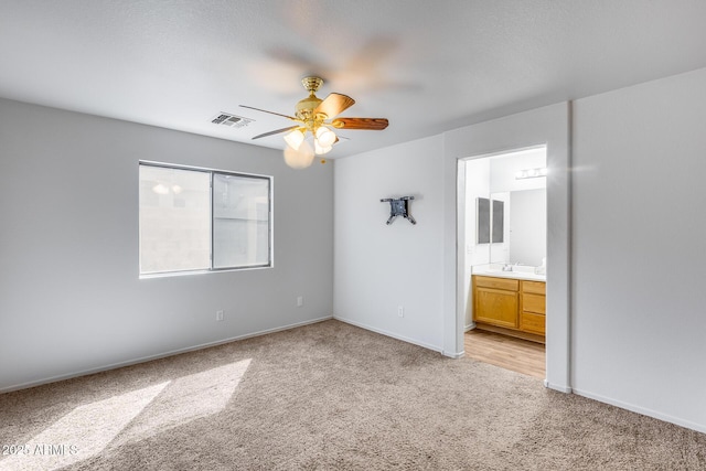 unfurnished bedroom featuring baseboards, visible vents, ensuite bath, a sink, and light carpet