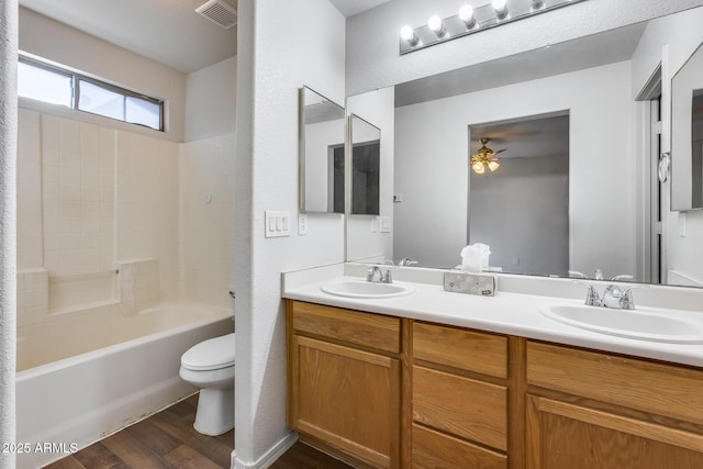 bathroom with toilet, wood finished floors, visible vents, and a sink