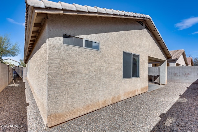 view of side of home featuring stucco siding, a patio, and a fenced backyard