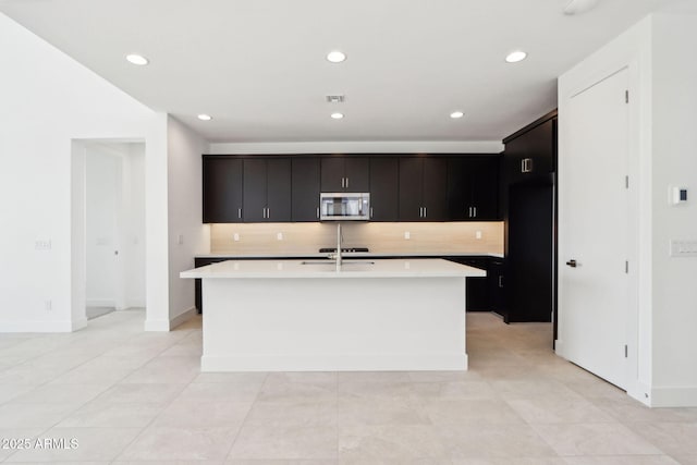 10253 E Ursula Ave, Mesa, AZ 85212 - kitchen with stainless steel microwave, light countertops, tasteful backsplash, a center island with sink, and recessed lighting