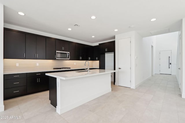 10253 E Ursula Ave, Mesa, AZ 85212 - kitchen featuring a sink, stainless steel microwave, light countertops, tasteful backsplash, and an island with sink