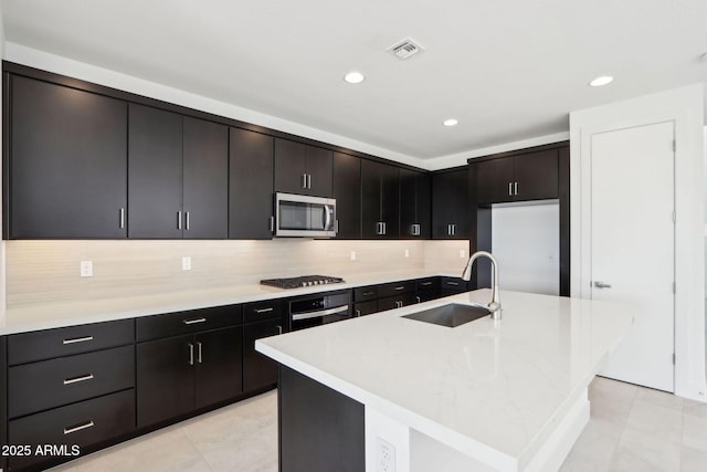 10253 E Ursula Ave, Mesa, AZ 85212 - kitchen featuring a sink, appliances with stainless steel finishes, light tile patterned flooring, decorative backsplash, and an island with sink