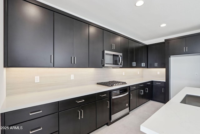 10253 E Ursula Ave, Mesa, AZ 85212 - kitchen with appliances with stainless steel finishes, light countertops, tasteful backsplash, dark cabinetry, and recessed lighting
