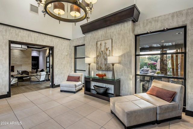 living area with a towering ceiling, a chandelier, and light hardwood / wood-style flooring