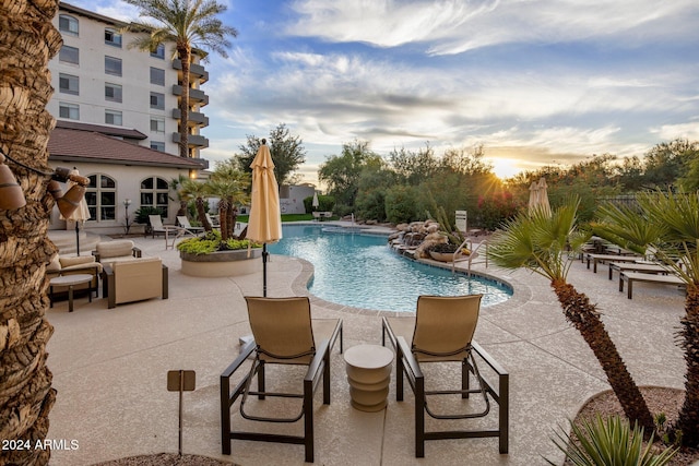 pool at dusk featuring a patio