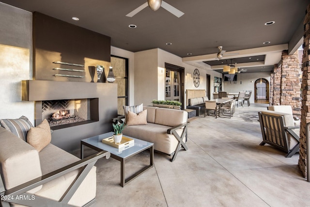 view of patio / terrace featuring ceiling fan and an outdoor living space with a fireplace