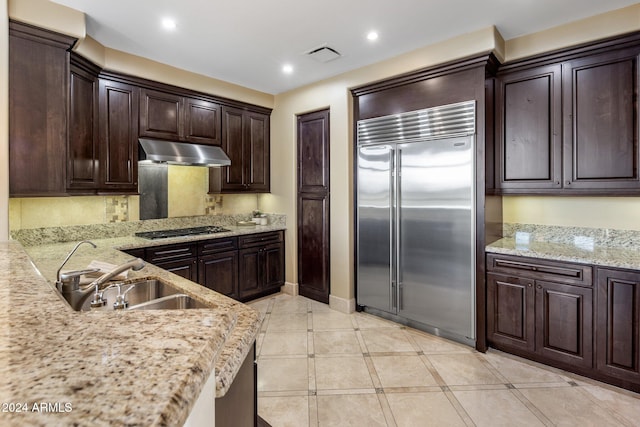 kitchen featuring dark brown cabinets, sink, light stone counters, and appliances with stainless steel finishes