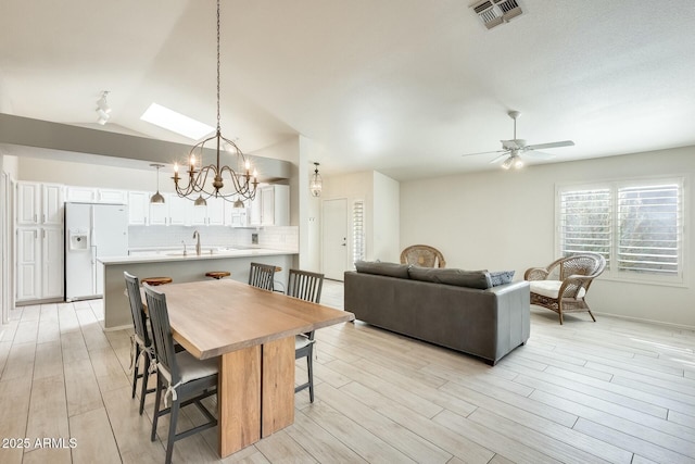 dining space featuring light wood finished floors, visible vents, and ceiling fan with notable chandelier