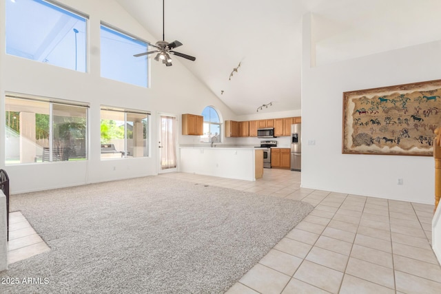 unfurnished living room with sink, high vaulted ceiling, light tile patterned flooring, and ceiling fan