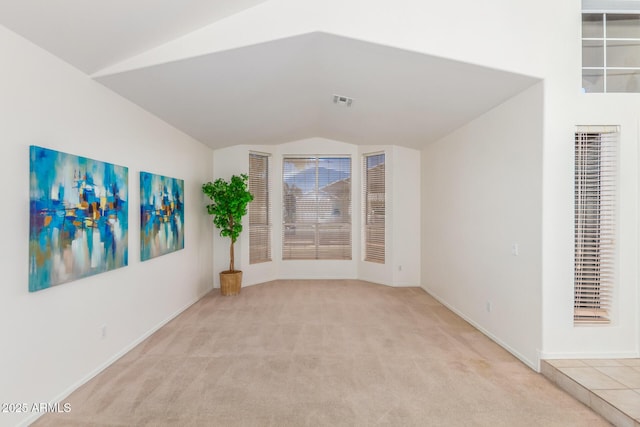 empty room featuring light colored carpet and lofted ceiling