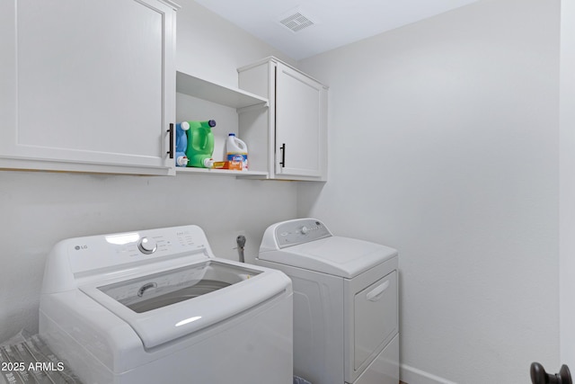 clothes washing area featuring visible vents, cabinet space, and separate washer and dryer