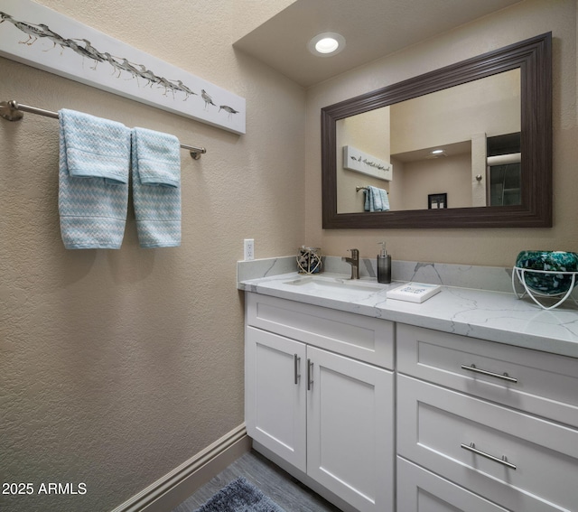 bathroom with vanity, baseboards, and a textured wall