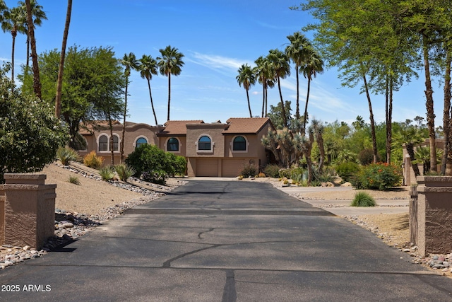 mediterranean / spanish-style home featuring a garage, driveway, and stucco siding