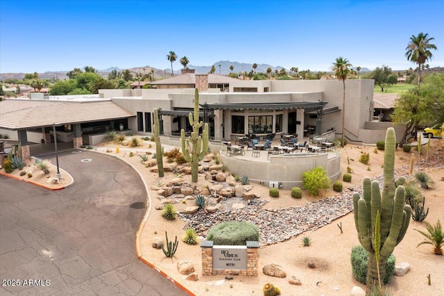 rear view of property featuring a mountain view, a chimney, a pergola, stucco siding, and a patio