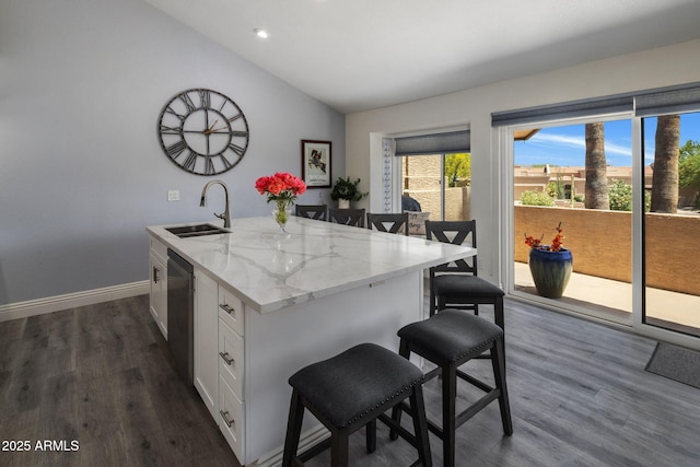 kitchen featuring a sink, lofted ceiling, a kitchen breakfast bar, white cabinetry, and dark wood finished floors