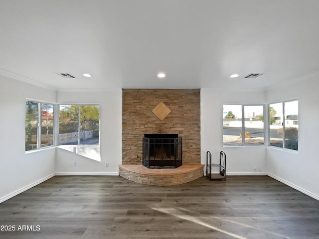 unfurnished living room featuring a stone fireplace, crown molding, and dark hardwood / wood-style floors