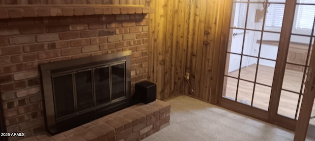 carpeted living room with a brick fireplace and wood walls