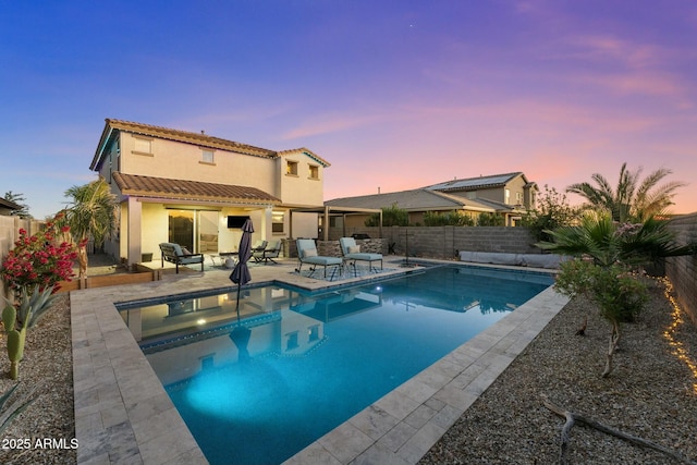 pool at dusk with an in ground hot tub and a patio area