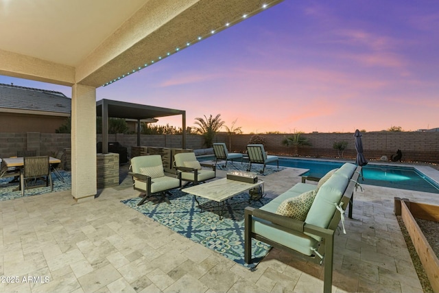 patio terrace at dusk featuring an outdoor living space and a fenced in pool